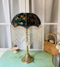 a table with a lamp on top of it next to a basket and window sill