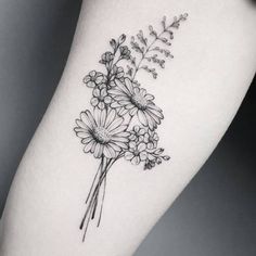 a black and white flower tattoo on the right thigh, with daisies in it