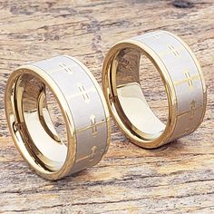 two gold wedding rings sitting on top of a wooden table