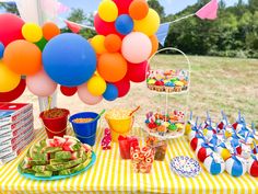 a table topped with lots of food and balloons