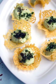 small appetizers are arranged on a plate with cheese and herbs in the middle