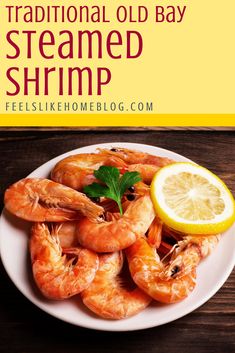 a white plate topped with cooked shrimp next to a lemon and parsley on top of a wooden table