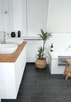 a bathroom with two sinks and a bathtub next to a stool in front of the tub