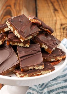 a white plate topped with lots of chocolate covered candy bar pieces on top of each other