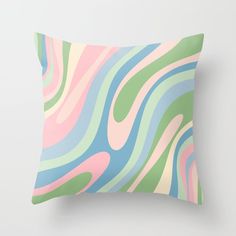 a pillow that is sitting on top of a white wall with a green, pink and blue swirl pattern