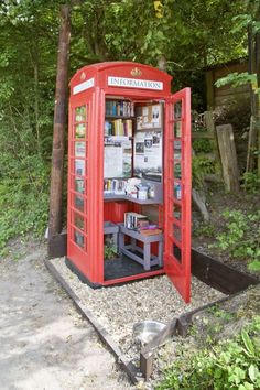 a red phone booth sitting in the middle of a forest