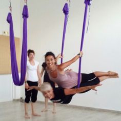 three women are doing aerial acrobatics in an empty room with purple ribbons