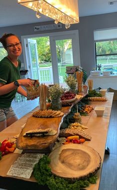 a woman standing in front of a table filled with different types of food on it