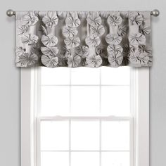 a window with a white curtain and flowered valance