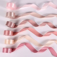 several different colored ribbons on a white surface with one pink and one beige ribbon in the middle