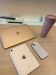 three apple laptops are sitting on a table next to a coffee cup and a cell phone