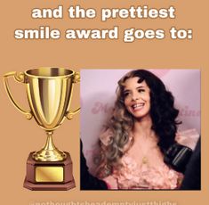 a woman with long hair standing next to a golden trophy and smiling at the camera