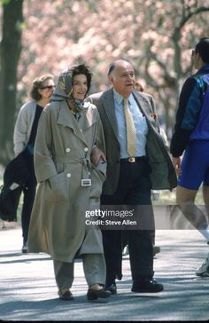 an older man and woman walking down the street in front of cherry blossom trees stock photo