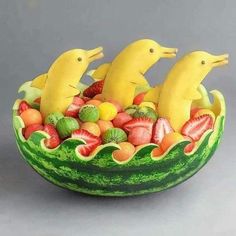 a fruit bowl with bananas, strawberries, melons and other fruits in it