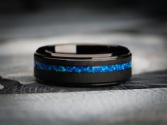 a ring with blue and black opal inlays on the inside of it