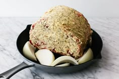 an iron skillet filled with food on top of a marble countertop next to utensils