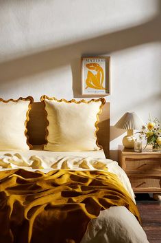 a bed with yellow and white comforters in a bedroom next to a lamp on a nightstand