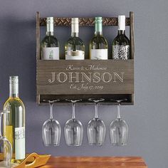 wine glasses and bottles are lined up on a wooden shelf above a bar with blue walls