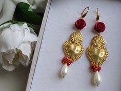 Extra long earrings made of: - Zama Brass Sacred Heart (47 mm x 370mm); - Smooth Mallorca Pearl drops (18 mm x 10 mm), white color; - Resin Roses; red color; - Bamboo Coral chips, red color; - Brass open hooks. Lenght : 12 cm / 4,72 inches * SHIPPING * Your order will be shipped within 1-3 business days from your purchase. You can choose between 2 shipping methods: STANDARD SHIPPING (without tracking) or REGISTERED MAIL (with tracking). Each chapeau atelier jewel is shipped in a gift box. Thank White Pierced Earrings For Valentine's Day, White Valentine's Day Earrings, Elegant Party Earrings With Heart Beads, Valentine's Day Celebration Dangle Earrings, Red Dangle Heart Earrings For Wedding, Red Heart Drop Earrings For Wedding, Red Drop Heart Earrings For Wedding, White Teardrop Jewelry For Valentine's Day, Pierced Jewelry For Wedding On Valentine's Day