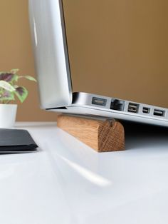 a laptop computer sitting on top of a white desk next to a potted plant