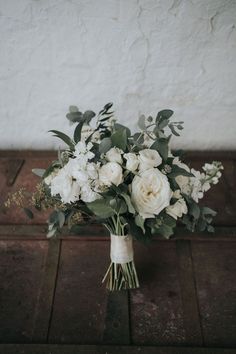 a bouquet of white flowers sitting on top of a wooden table