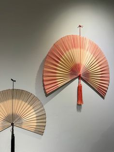 two fan hanging on the wall next to each other in front of a white wall