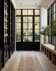 a hallway with black doors and large windows next to a long rug on the floor