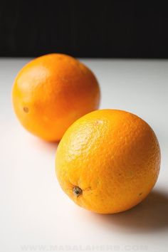 two oranges sitting next to each other on a table