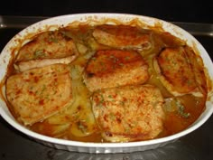 some meat and vegetables in a white dish on a stove top with gravy