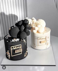 two black and white cakes sitting on top of a table next to each other,