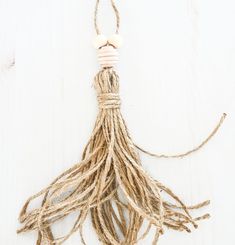 a tasseled piece of rope hanging from a string on a white wooden surface