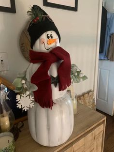 a snowman with a scarf and hat on top of a dresser