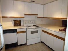 an empty kitchen with white appliances and cabinets