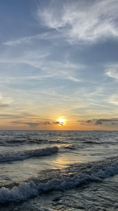 the sun is setting over the ocean waves