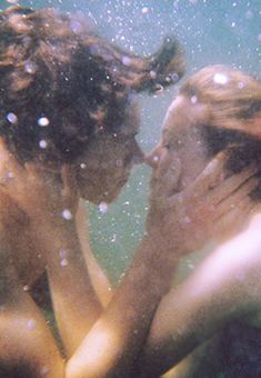 two people are under the water with their faces close together