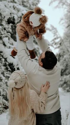 a man holding a teddy bear up to his face while another woman holds him in the air