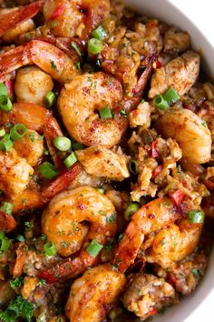 a white bowl filled with shrimp and rice covered in green onion garnishments