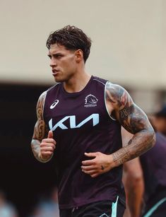 a man with tattoos running on a track