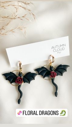 the earrings are black with red flowers on them and gold hoops, along with a white card that says autumn cloud