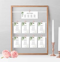 a wooden frame with seating cards and candles on it, next to a pink rose