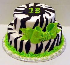 a zebra print cake decorated with green and white icing, bows and number 13