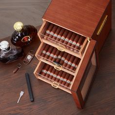 an open wooden box with cigars and other items on the table next to it