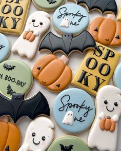 decorated cookies with bats and ghostes are on a white tablecloth that says spooky kory