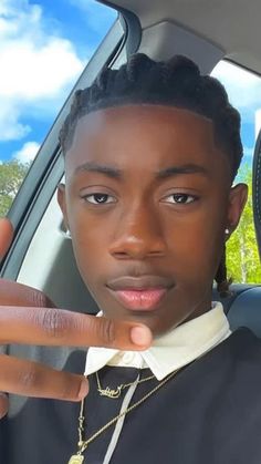 a young man sitting in the back seat of a car making a peace sign with his fingers