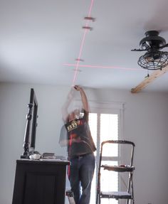 a man standing in front of a tv holding a red light up to the ceiling