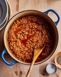 a large pot filled with chili next to two wooden spoons on top of a table