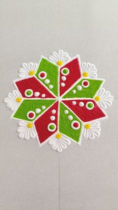 a red, green and white christmas ornament hanging on a wall with snowflakes