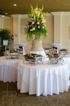 a table topped with lots of food covered in white cloths and flowers on top of it