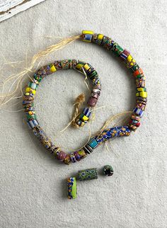 You will receive this strand of African trade beads.  There are 70 beads, some have come off the raffia strand, most are small, some medium sized.  These beads are old and they are in good condition with ap appropriate amount of wear for age. We have rebranded, and since December 2023 we are Lazy Frog Thrifters.  We have been flipping high end home decor that we find at thrift stores, yard sales, flea markets, and estate sales.  Come check out the old and tired items that we have given a French Country look or Cottage Core vibe to at:  https://lazyfrogthrifters.etsy.com Vintage Multicolor Spacer Beads, Traditional Hand-strung Beads For Crafting, Mixed Spacer Beads For Jewelry Making, Traditional Heishi Beaded Necklaces, Artisan Heishi Beads, Handmade Heishi Oval Beads, Handmade Oval Heishi Beads, Vintage Wooden Round Beads, Vintage Multicolor Beads For The Beach