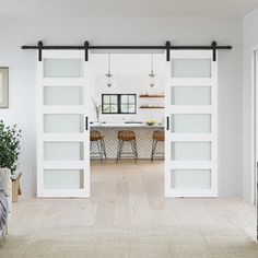 an open living room with sliding doors leading to the kitchen and dining area in the background